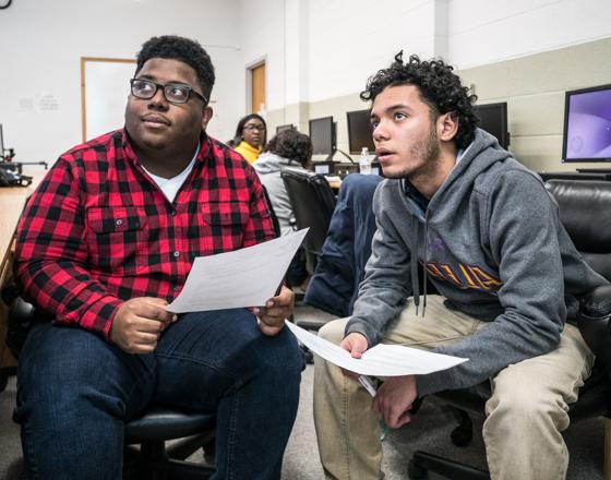 Two students with papers in their hands