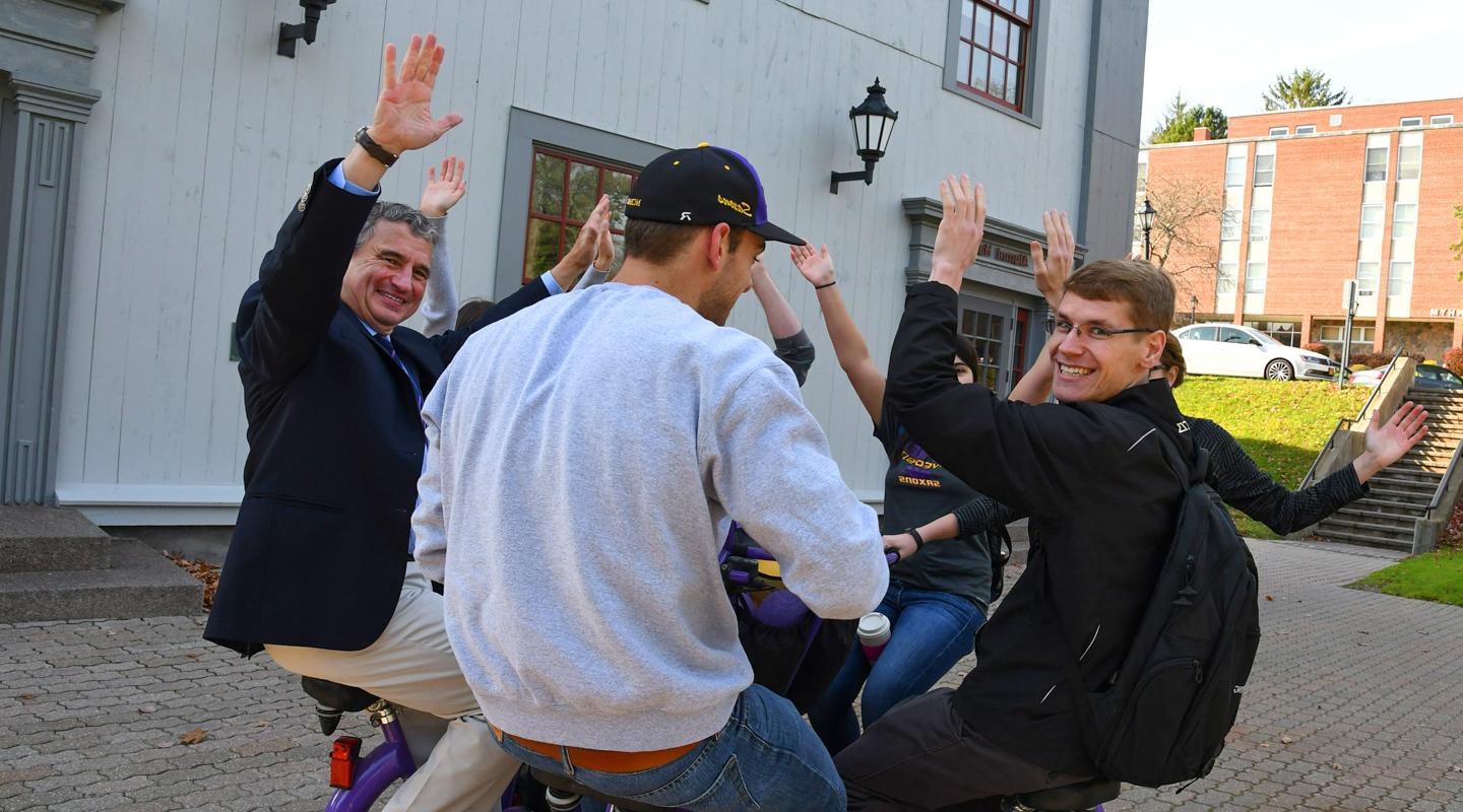 Students and President Zupan riding a bike. 